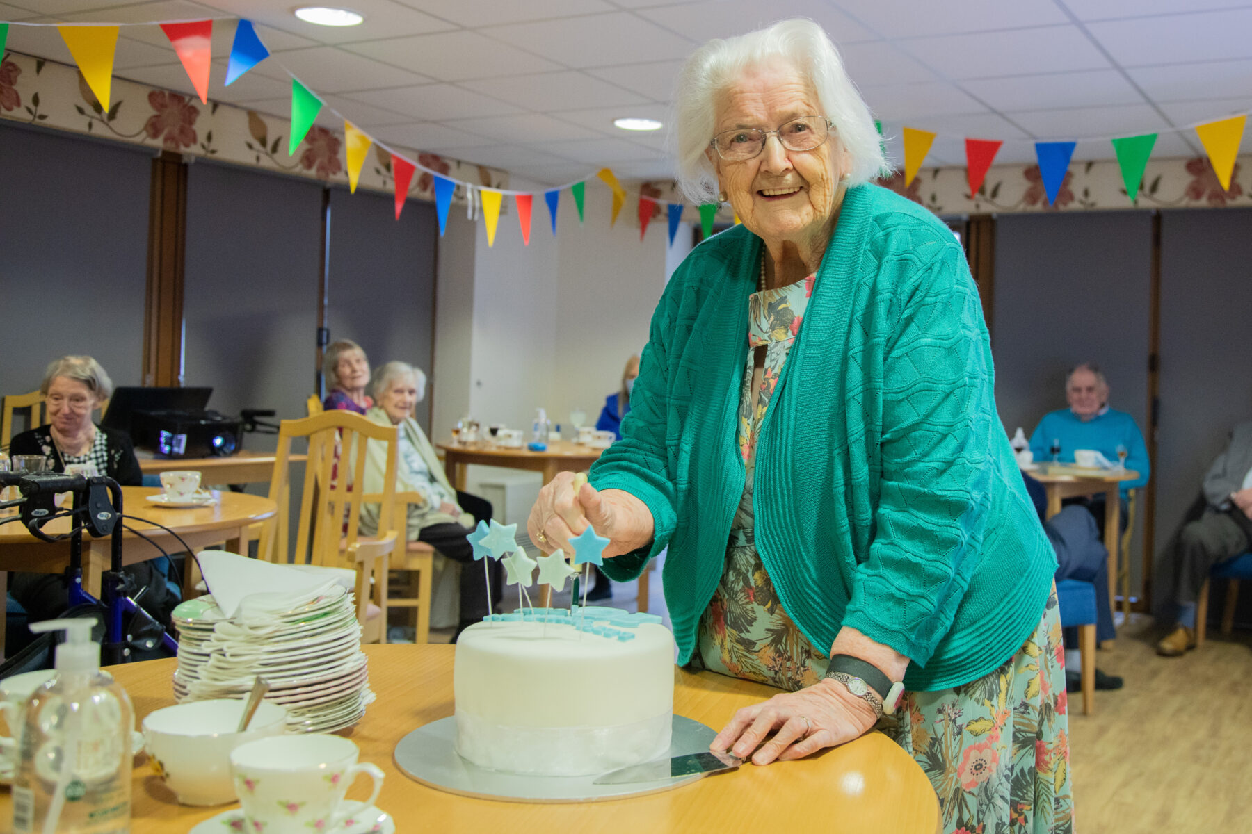 One of the Llys Awelon residents cutting a celebration cake